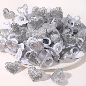 Détail de chouchous cœur à paillettes argentées avec élastiques blancs sur plateau