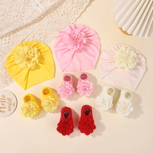 Detalle de conjunto de gorros y calcetines para bebé con flores en algodón suave