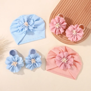 Flat lay of baby hat and foot cover sets in light blue and pink with large fabric flowers