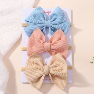 Three-piece baby bow headbands in blue, pink, and beige waffle fabric on display card
