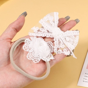 Detail of baby headband featuring white lace floral bow and soft elastic nylon band