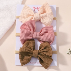 Detailed view of three baby bow headbands with waffle texture on white display card