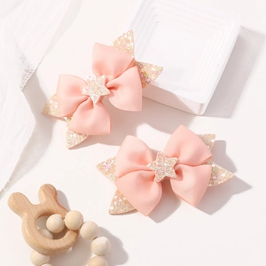 Close-up of pink grosgrain bow hair clips with glitter star accents for girls