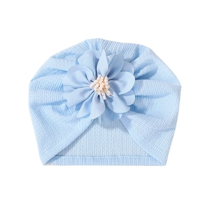 Light blue knit baby turban hat with decorative floral detail on white background