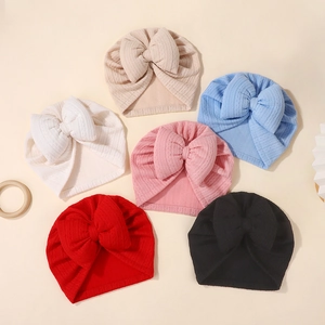 Flat lay of six colorful knitted baby hats featuring oversized bows and jacquard textures