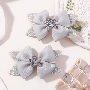 Close-up of silver-gray grosgrain ribbon bow hair clips with glitter stars for girls