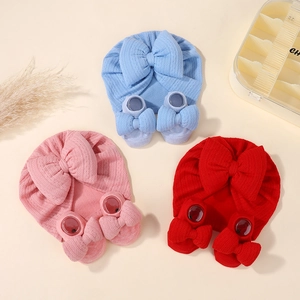 Detail view of baby bow turban and matching socks in blue, pink, and red knitted fabric