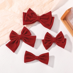 Detail of four dark red velvet bow hair clips with soft texture for girls