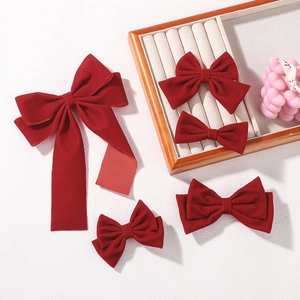 Detailed collection of deep red velvet bow hair clips on a textured background with props