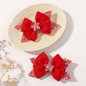 Detail view of two cute red ribbon hair clips with glitter star and pink sequin base