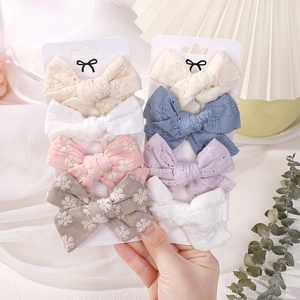 Detailed close-up of 8-piece set of embroidered floral cotton bow hair clips for girls