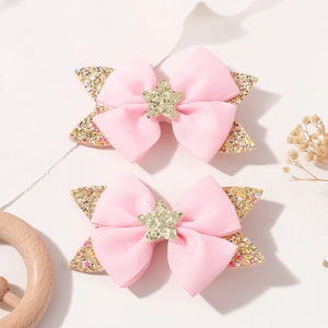 Detailed macro shot of pink ribbon hair clips with gold glitter stars for girls