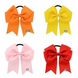 Detailed macro view of four grosgrain ribbon hair bows in orange, yellow, pink, and red
