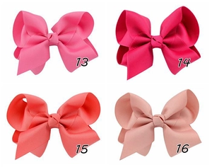 Detail view of four colorful grosgrain ribbon hair bows in pink and red shades