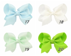 Close-up of ribbed fabric hair bows in light blue, white, mint green, and emerald colors