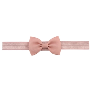 Détail d'un bandeau élastique rose poudré pour bébé avec un nœud en tissu côtelé doux