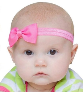 Gros plan d'un bandeau à nœud rose vif sur un bébé pour un look élégant