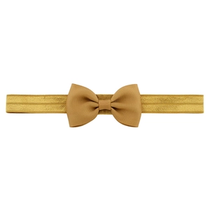 Close-up of golden ribbed fabric bow headband showing detailed texture and elastic band