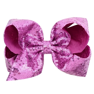 Detail of 8-inch bright fuchsia sequin hair bow with shimmering texture on white background