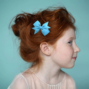Détail d'un nœud papillon bleu clair en ruban gros-grain sur les cheveux d'une fille