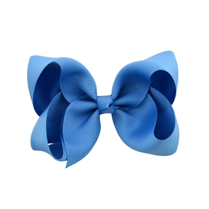 Dettaglio di un fermaglio per capelli con fiocco in nastro grosgrain blu e trama a costine