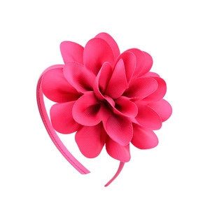 Detalle de la flor multicapa hecha a mano en cinta rosa roja sobre la diadema infantil
