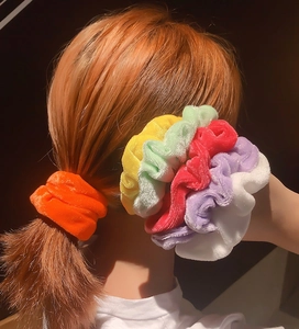 Detailed view of velvety scrunchies in candy colors on orange hair ponytail