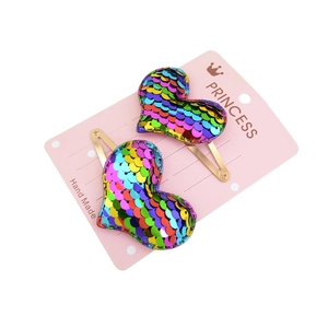 Pair of heart-shaped rainbow sequin hair clips for children on pink display card