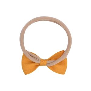 Détail d'un bandeau élastique pour bébé en nylon avec un grand nœud en gros-grain jaune