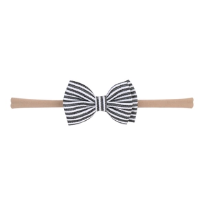 Détail du bandeau bébé en nylon avec nœud rayé noir et blanc sur tissu beige doux