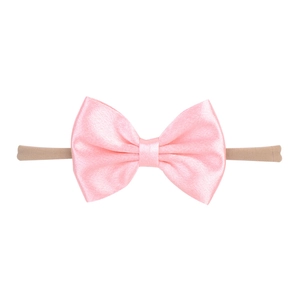 Détail d'un nœud en satin rose sur un bandeau élastique en nylon pour bébé
