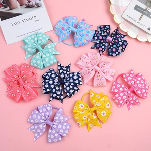 Flat lay of floral grosgrain ribbon fishtail bow hair ties set on a pink background