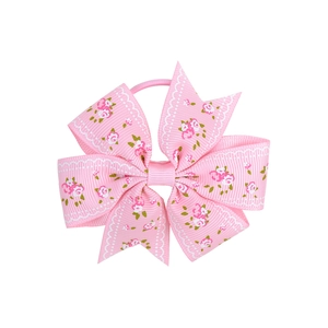 Detail of pink floral grosgrain ribbon hair bow with white lace print and elastic band