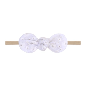 Detail of baby headband featuring white eyelet lace bow and nude nylon elastic band