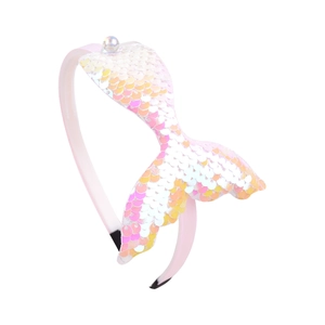 Détail de la queue de sirène à paillettes irisées sur un serre-tête rose avec une perle