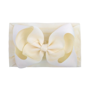 Detailed macro view of the cream nylon baby headband with a large textured ribbed bow