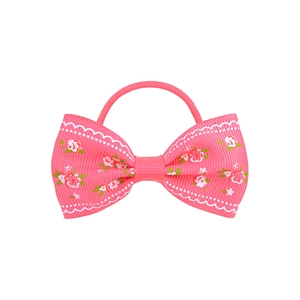 Détail d'un chouchou rose en gros-grain avec imprimé floral et bordures blanches ondulées