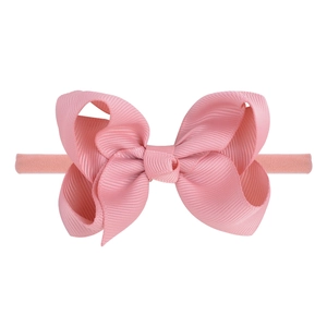 Close-up of pink grosgrain ribbon bow headband with detailed texture and elastic band