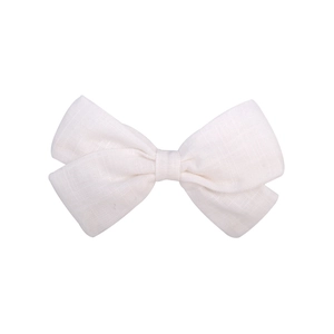 Close-up of a white cotton fabric bow hair clip showing detailed linen textile texture