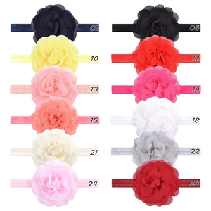 Flat lay display of 12 colorful chiffon flower headbands for babies on white background