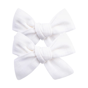 Vue détaillée des barrettes nœuds en tissu blanc montrant la texture du coton tissé