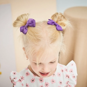 Set of two purple grosgrain ribbon hair bow clips on a young girl with hair buns