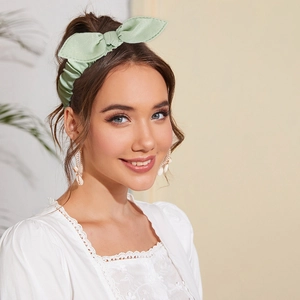 Detail of light green knotted bunny ear headband with soft pleated fabric texture