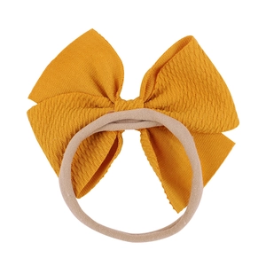 Detail of soft bright yellow bow headband with flexible elastic beige nylon strap