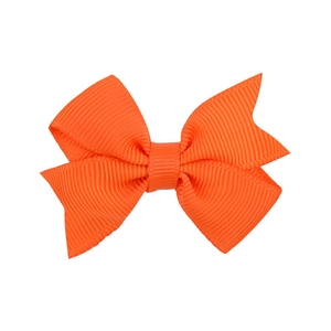 Macro detail of high-quality bright orange grosgrain fabric on the classic bow hair clip