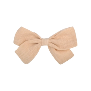 Close-up of peach linen bow hair clip showing cross-weave texture and natural fabric grain