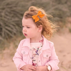 Primo piano di una bambina con un fiocco per capelli in gros-grain arancione all'aperto