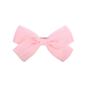 Close-up of pink linen fabric hair bow clip with natural fiber texture and vintage style