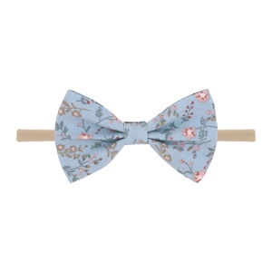 Détail d'un bandeau floral pour bébé avec fleurs roses sur tissu bleu et élastique nylon