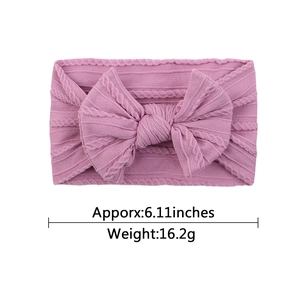 Pink jacquard knit baby headband with a large soft bow and cable texture design